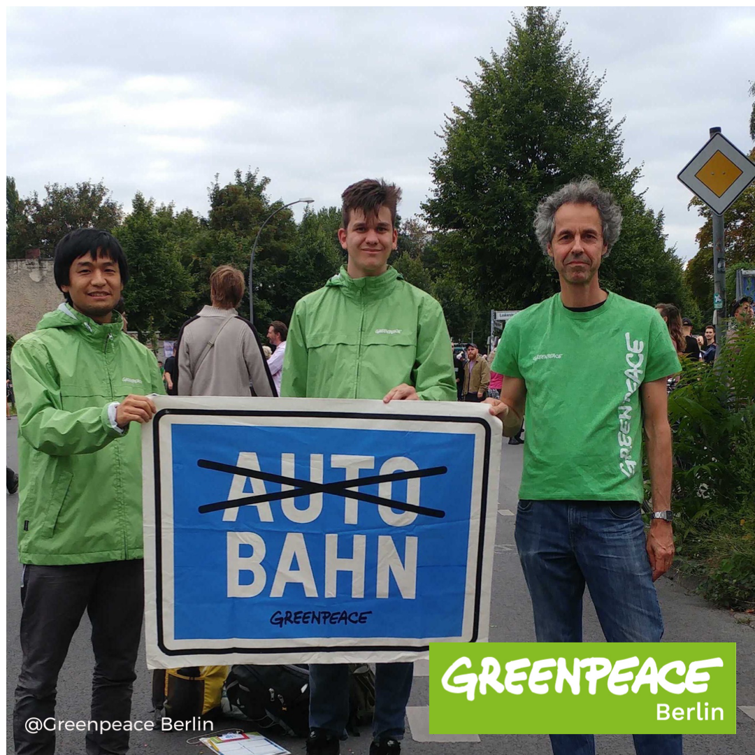 Drei Aktivist:innen von Greenpeace halten ein Schild mit der Aufschrift Auto Bahn in zwei Zeilen. Schwarz durchgestrichen ist das Wort Auto.